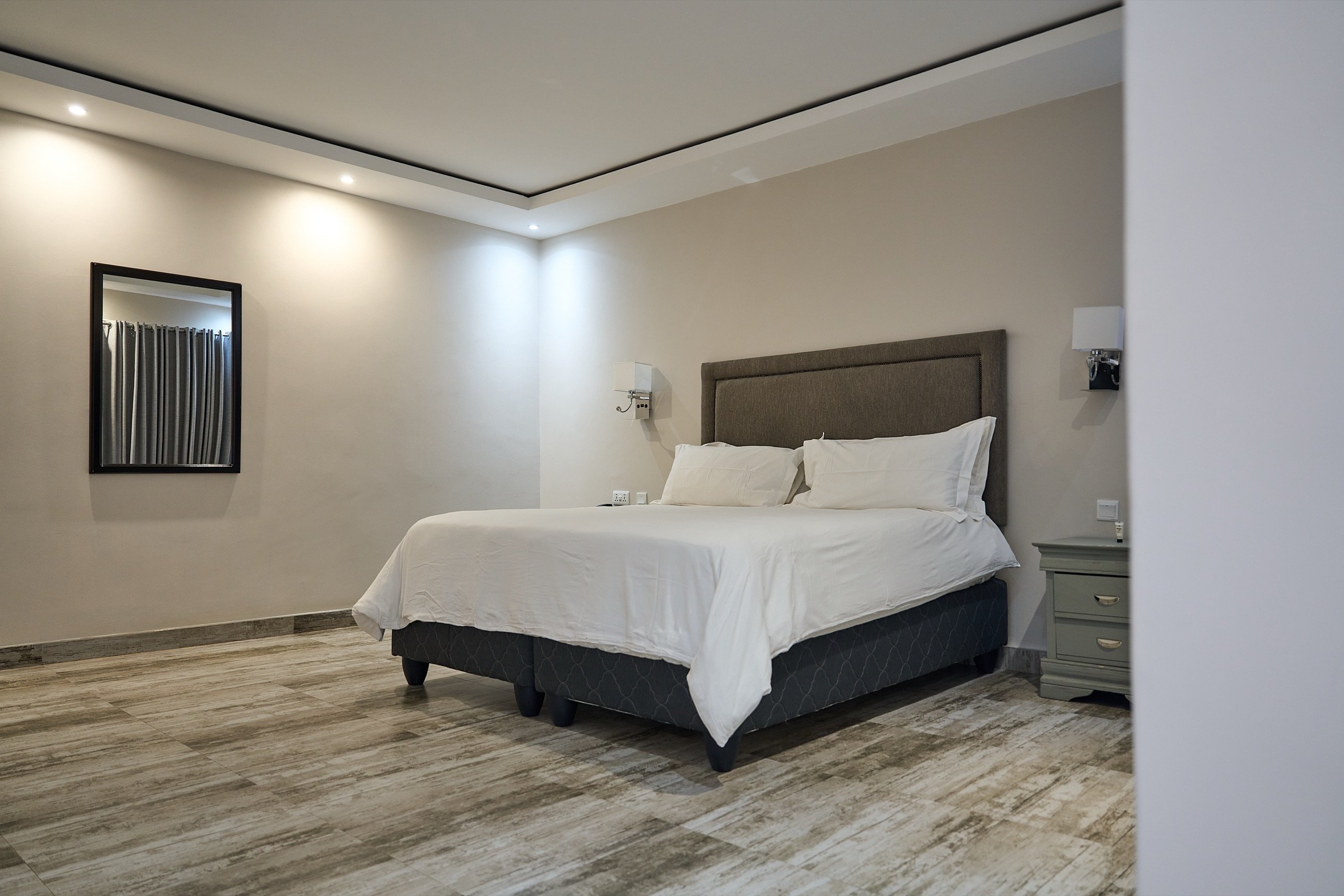 Bed with grey upholstered headboard and framed wall mirror