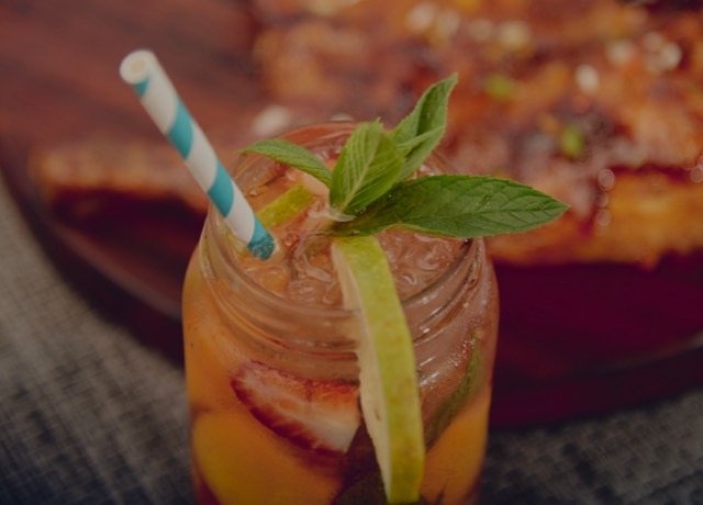 Iced drink in a mason jar with mint, lime and strawberry