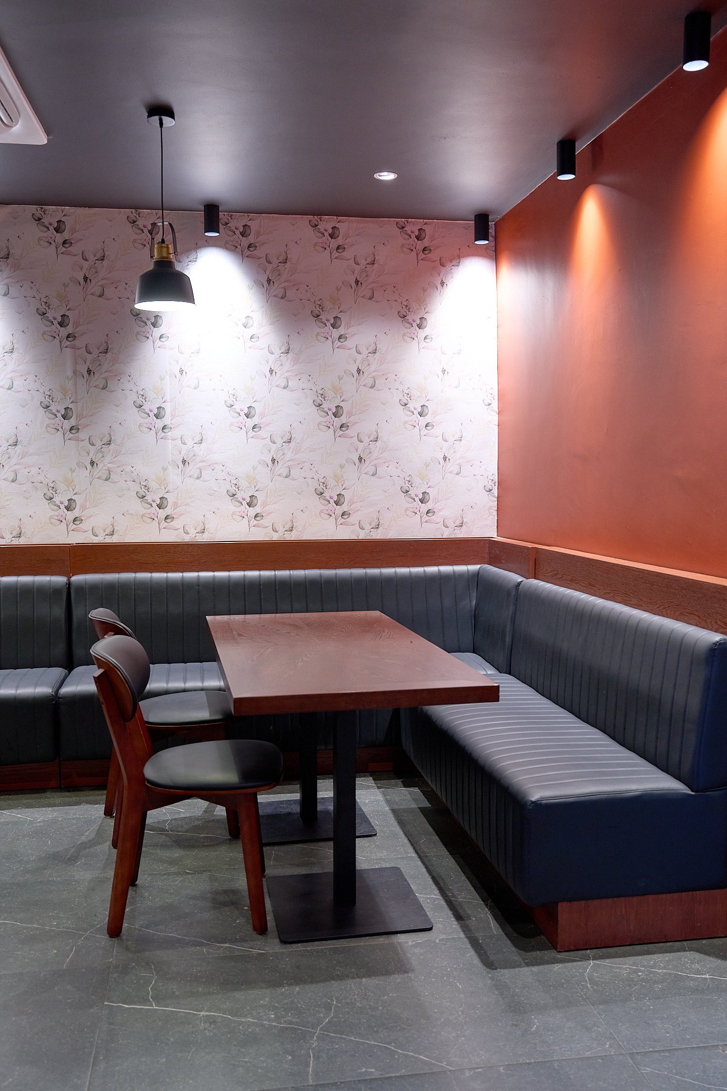Enclosed booth nook with wood-slat walls and a hanging pendant lamp