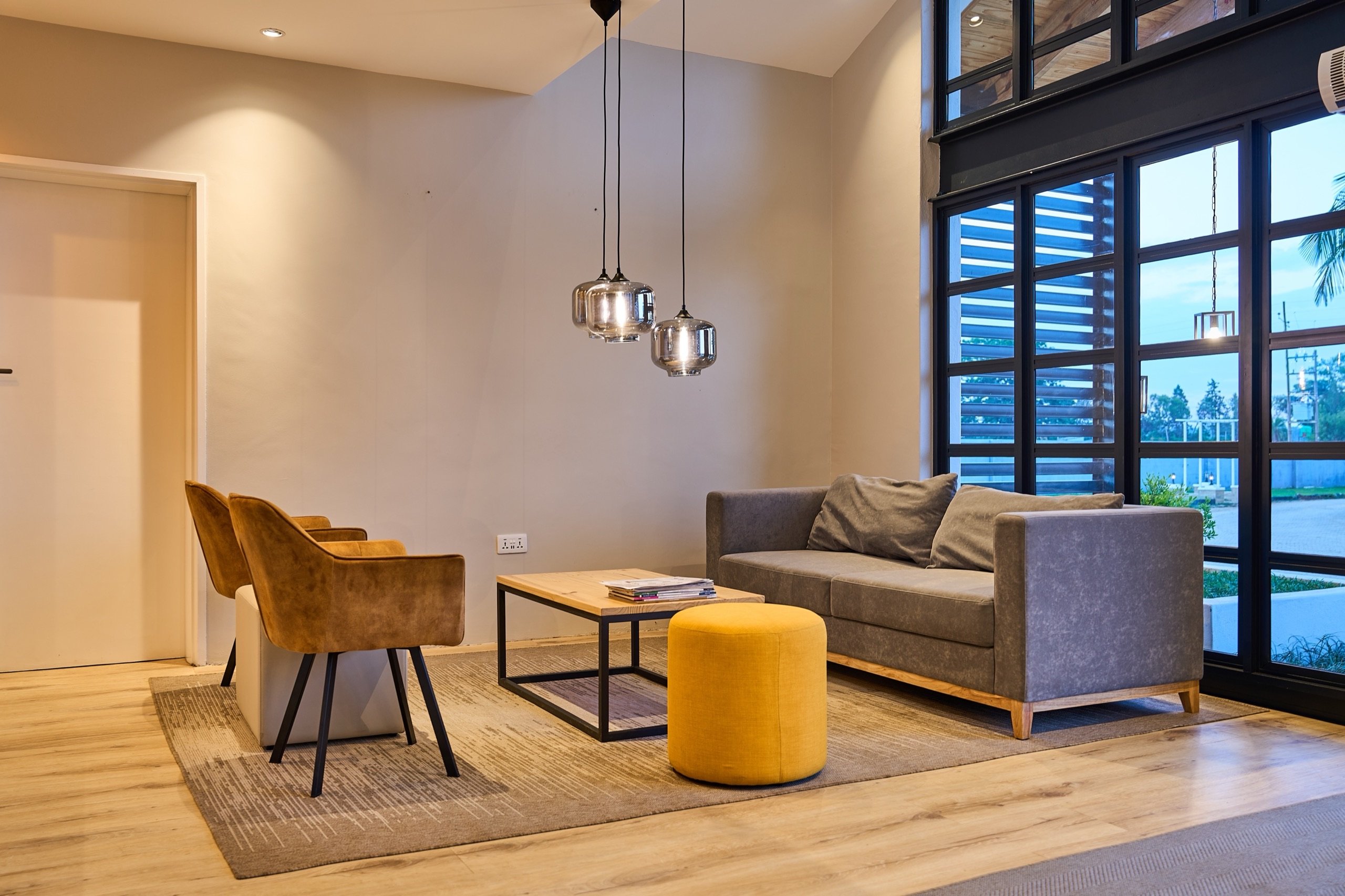 Lounge seating with tan armchairs, grey sofa and yellow pouf around a coffee table